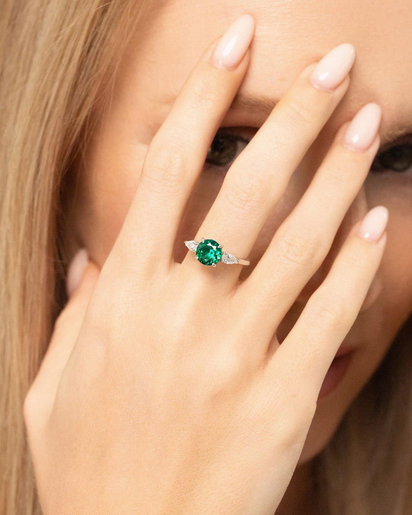 Anillo de compromiso de tres piedras con corte redondo de esmeralda en plata de ley