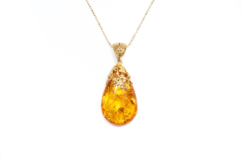 Colgante con gota ámbar y acento floral dorado