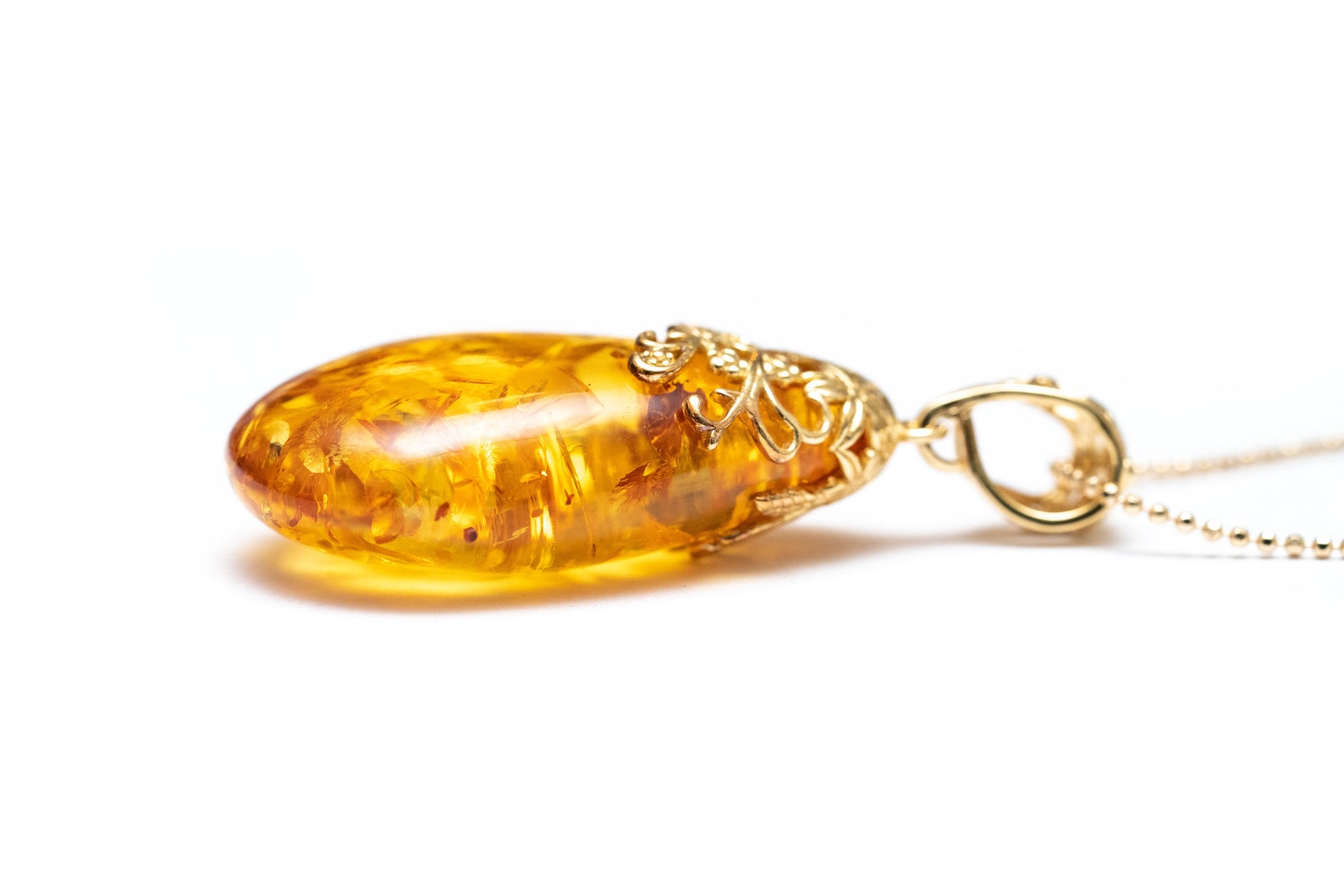 Colgante con gota ámbar y acento floral dorado