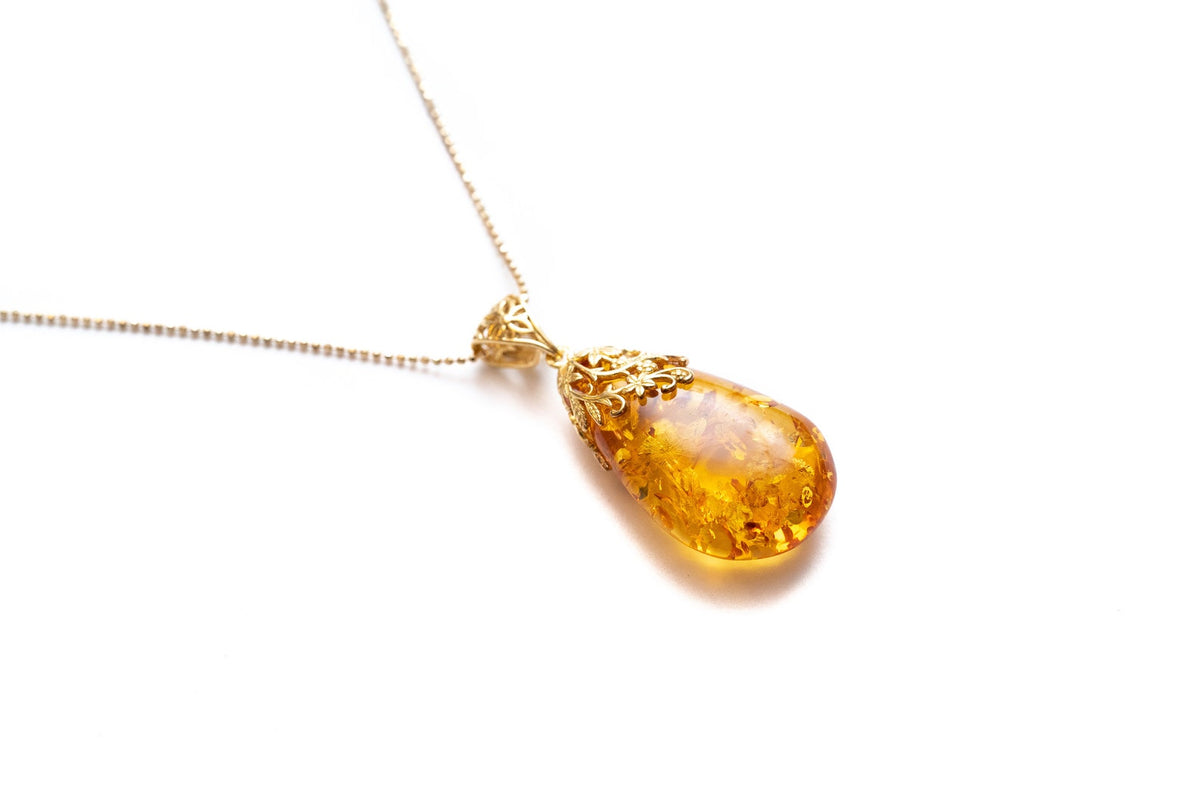 Colgante con gota ámbar y acento floral dorado