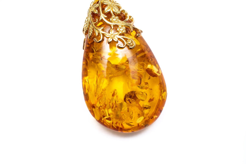 Colgante con gota ámbar y acento floral dorado