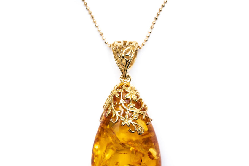 Colgante con gota ámbar y acento floral dorado