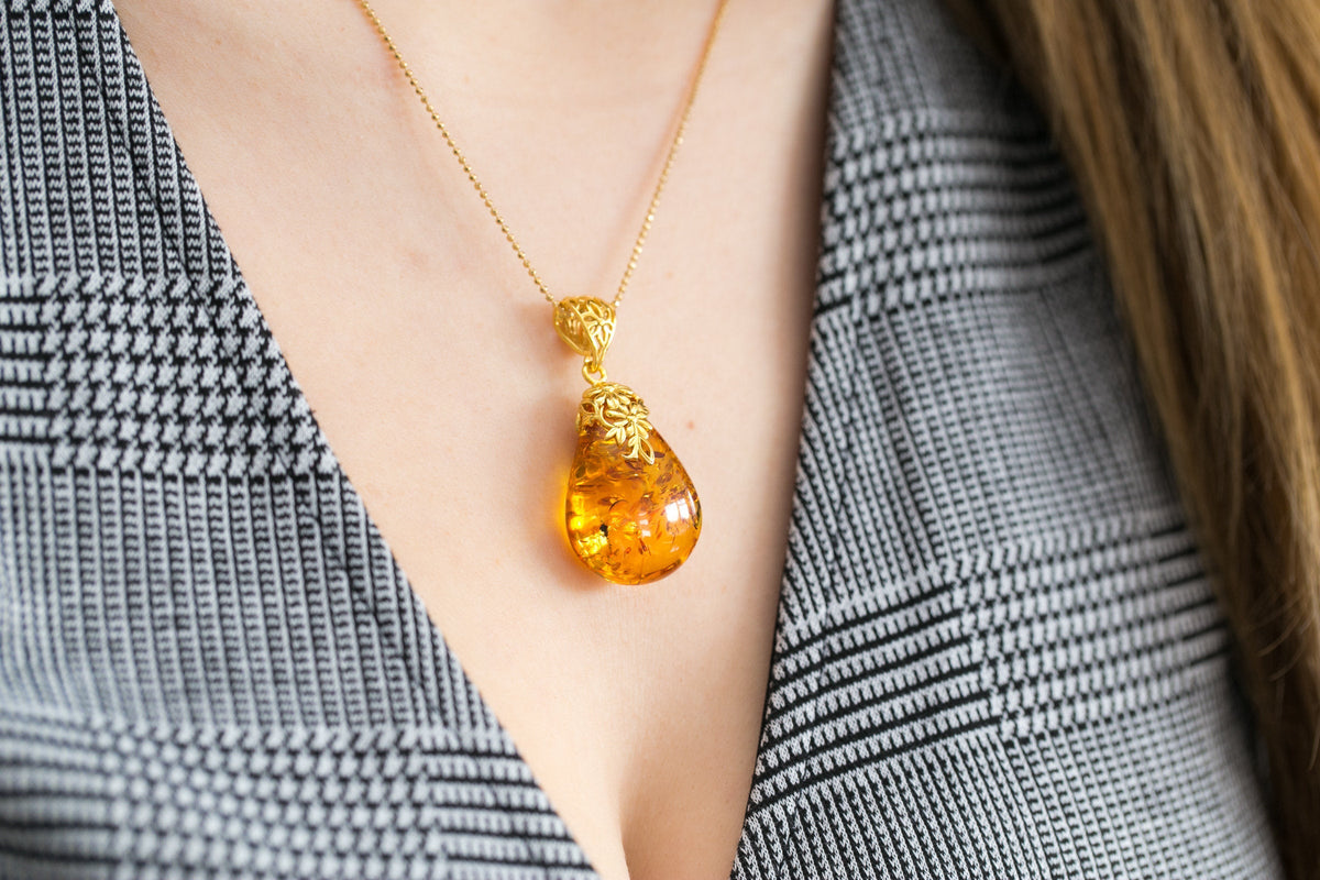 Colgante con gota ámbar y acento floral dorado