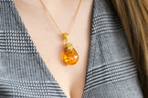 Colgante con gota ámbar y acento floral dorado