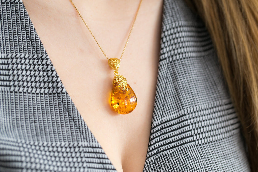 Colgante con gota ámbar y acento floral dorado